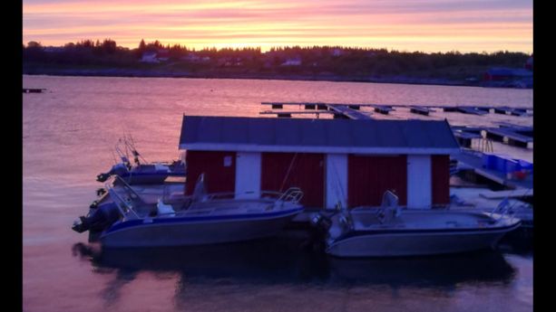 Et hus på en brygge i solnedgangen med båter lagt til