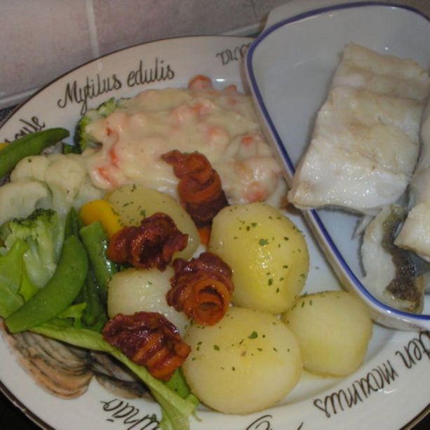 En fiskerett med torskfillet, potet, saus, salat og diverse tilbehør